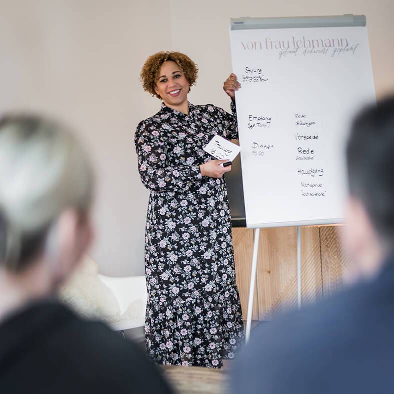 Frau Lehmann mit Flip-Chart zeigt Brautpaar Präsentation